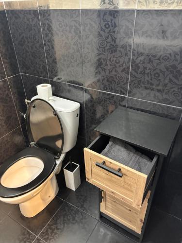 La salle de bains est pourvue de toilettes avec un couvercle noir et un tiroir en bois. dans l'établissement Studio cosy à 400m de la plage - Lumineux et comfortable, à Menton