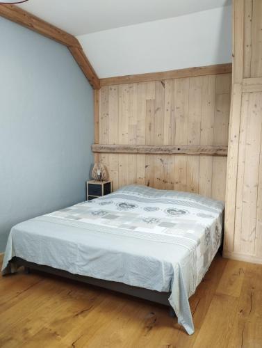 - une chambre avec un lit et un mur en bois dans l'établissement L'Echapée belle, au Bourg-dʼOisans