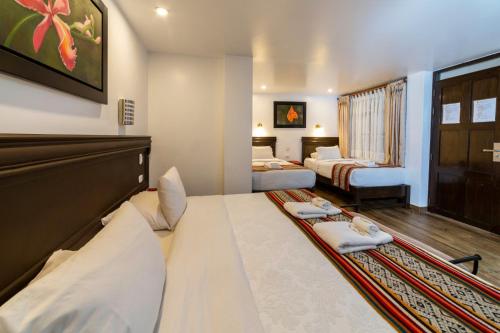a hotel room with two beds and a couch at Gringo Bill's Boutique Hotel in Machu Picchu