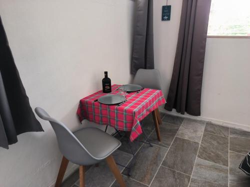 a table with a bottle of wine and two chairs at studio Caraïbes in Les Trois-Îlets