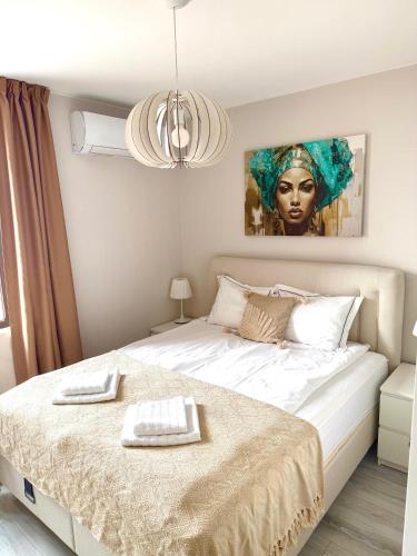 a bedroom with a large white bed with a painting on the wall at ORA SeaView in Balchik