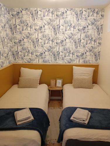 - 2 lits jumeaux dans une chambre avec papier peint dans l'établissement Les meublés de Louis-Marie, 2 appartements indépendants pour 4 personnes, 8 personnes au total, proche du Puy du Fou, à Saint-Amand-sur-Sèvre