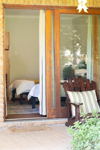 a glass door of a porch with a chair and a bed at Aan d'Oewer in Citrusdal