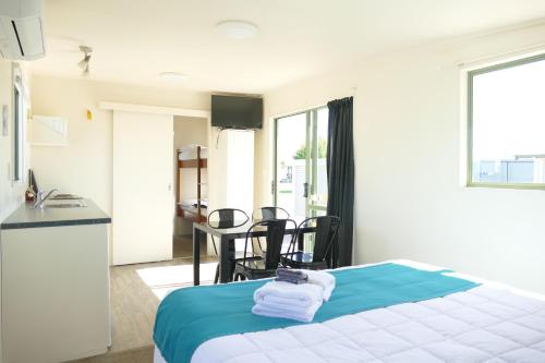 a bedroom with a bed and a table and chairs at Riverside Whakatane Holiday Park in Whakatane