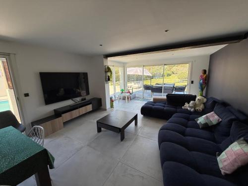 un salon avec un canapé bleu et une télévision dans l'établissement VILLA piscine au GOLF, à Baillargues