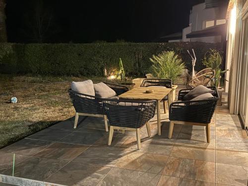 - une table et des chaises en bois sur une terrasse la nuit dans l'établissement VILLA piscine au GOLF, à Baillargues