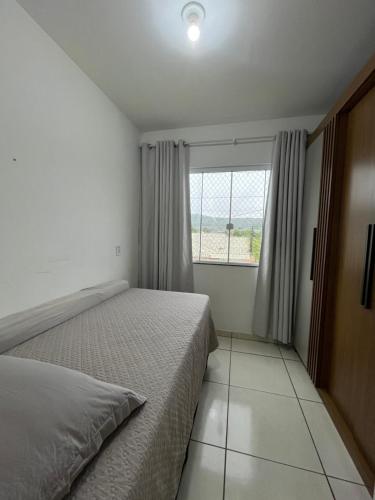 ein Schlafzimmer mit einem Bett und einem großen Fenster in der Unterkunft Aconchegante Cantinho 202 in Penha