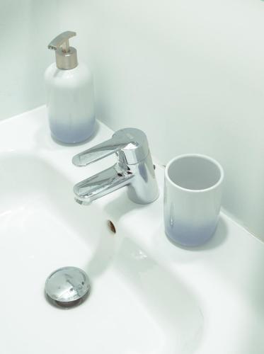 a bathroom sink with a cup and a faucet at Only for Women Hostel Madrid-Sol in Madrid