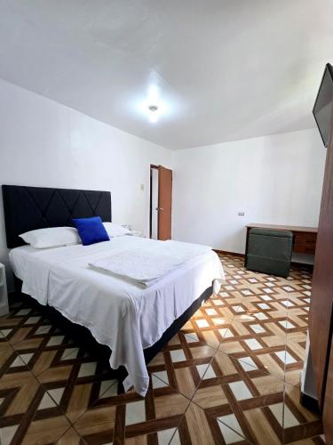 a bedroom with a large white bed with blue pillows at Los Angeles Hotel in Huaral