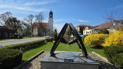 a statue in the grass with a clock tower in the background at Apartamenty Rynek 3 Czerwony in Osie