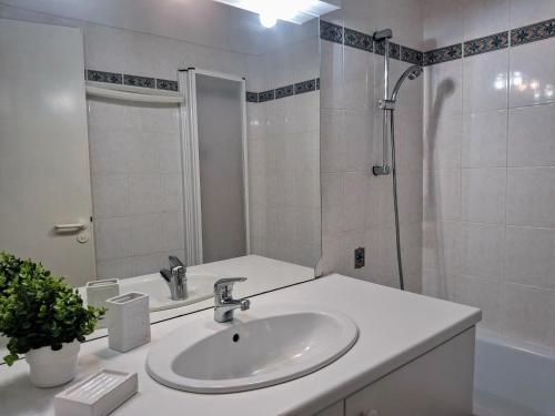 une salle de bain blanche avec un lavabo et une douche dans l'établissement Appartement plein centre quartier des thermes, à Saint-Lary-Soulan