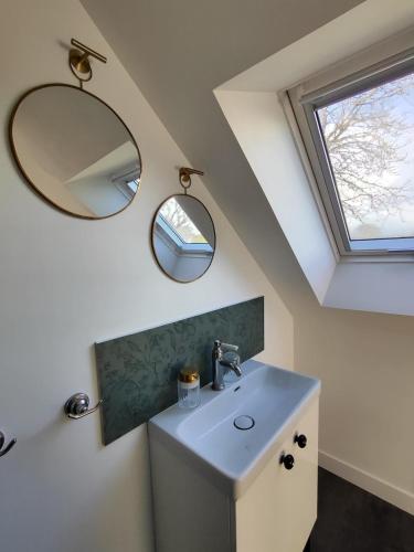 une salle de bain avec un lavabo et un miroir dans l'établissement Tata Jacqueline, grand gîte proche mer, Bretagne, à Plouha