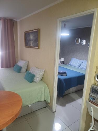 una camera da letto con due letti, un tavolo e uno specchio di Apartment 209 a Santiago