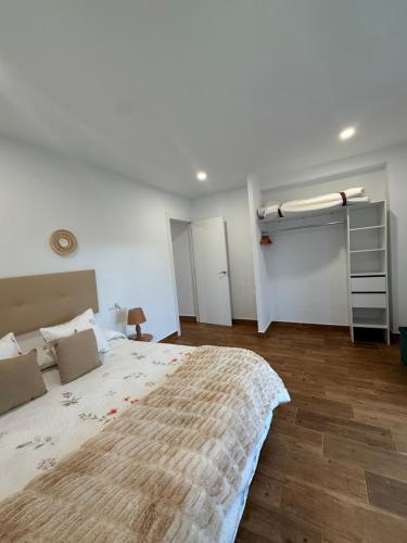 a white bedroom with a large bed and a ladder at La casuca de Candela in Santillana del Mar