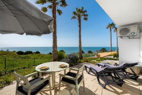 a patio with a table and chairs and palm trees at Nativo Big Wave Front Row - 1BR in Nazaré
