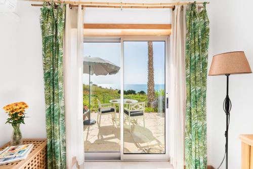 a room with a door open to a patio with a table at Nativo Big Wave Front Row - 1BR in Nazaré