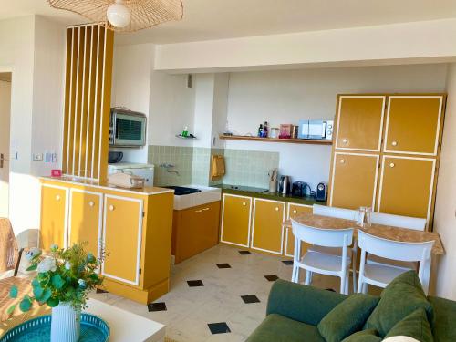 une cuisine avec des armoires jaunes et un canapé dans une pièce dans l'établissement L'appart du Val, Vue mer, à Pléneuf-Val-André