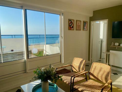 - un salon avec une table, des chaises et une grande fenêtre dans l'établissement L'appart du Val, Vue mer, à Pléneuf-Val-André