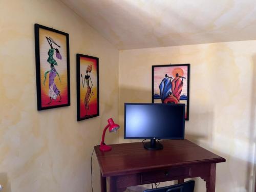 a television on a table with pictures on the wall at Villa Mamma Francesca in Salemi
