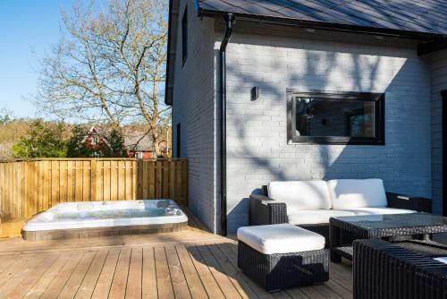 a patio with a couch and a bench on a deck at Nyrenoverad villa med spabad i Mörrum in Mörrum