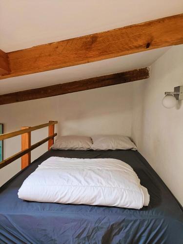 Ce lit se trouve dans une petite chambre dotée d'un plafond en bois. dans l'établissement charmant T1, au Grau-dʼAgde