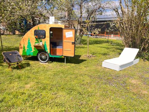 a small yellow and green trailer with a chair and a table at Tinydorf XXS in Sinsheim