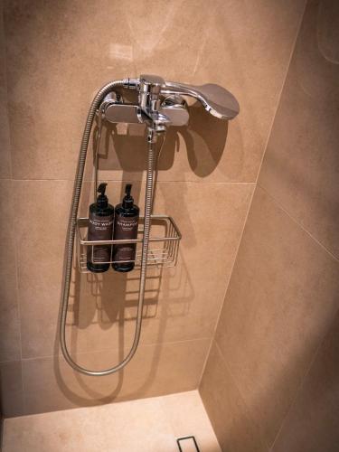 a shower with three bottles on a rack in a bathroom at White luxury apartment in Tríkala