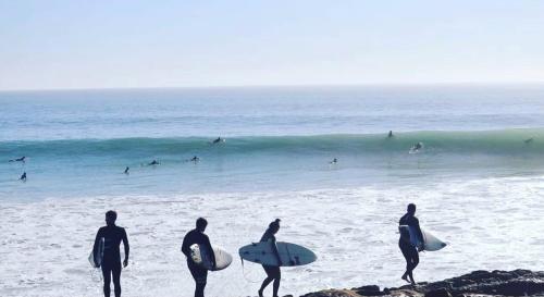 a group of people standing on the beach with surfboards at Four Seasons Apartment in Agadir