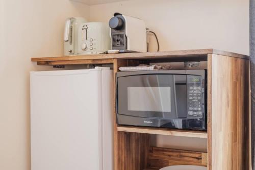 a microwave sitting on a shelf next to a refrigerator at Orion Suite - Compact Stay with Essentials in Lake Tekapo