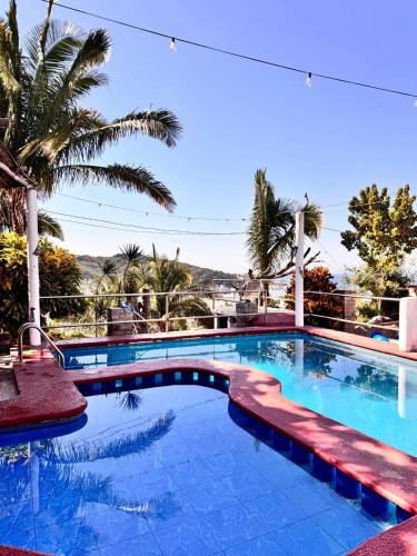 a swimming pool with palm trees in the background at Las Cabañas del Tio Lalo in Rincon de Guayabitos