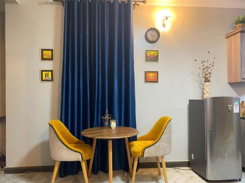 a table and two chairs and a blue curtain at Bree's Residence in Buwate