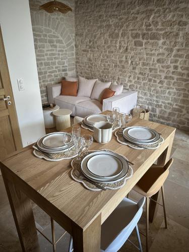une table en bois avec des assiettes et des verres à vin dessus dans l'établissement Chai rénové plein centre à 5minutes à pied de la plage, à Sainte-Marie de Ré