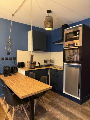 une cuisine avec des murs bleus et une table en bois dans l'établissement Le Corsaire, à Lourdes