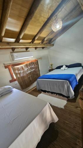 een slaapkamer met 2 bedden en een kroonluchter bij Chalé do vini in Prado