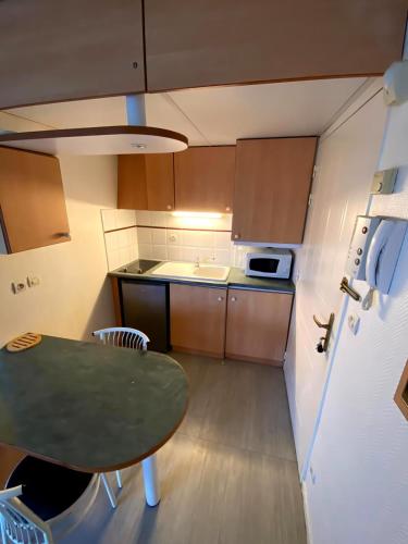 une petite cuisine avec une table et un réfrigérateur dans l'établissement T2 avec parking sous sol et piscine dans résidence, à La Rochelle