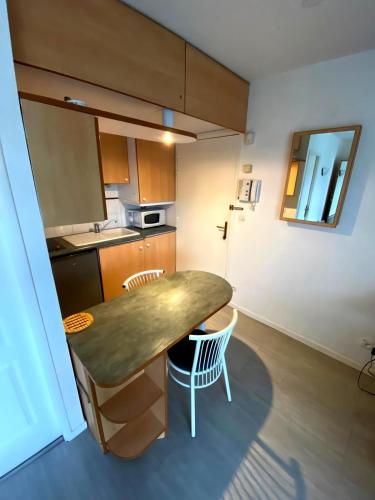 une petite cuisine avec une table et des chaises. dans l'établissement T2 avec parking sous sol et piscine dans résidence, à La Rochelle