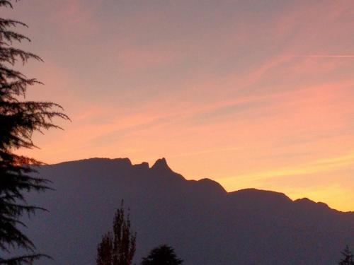 un coucher de soleil avec une montagne en arrière-plan dans l'établissement Confortable, au calme avec jardin, jolie vue - G3, à Aix-les-Bains