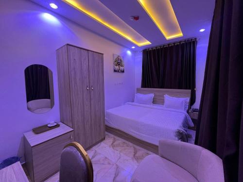 Un dormitorio con una cama, un televisor y sillas. en Grand Lynks Homes and Apartments, en Gwarinpa
