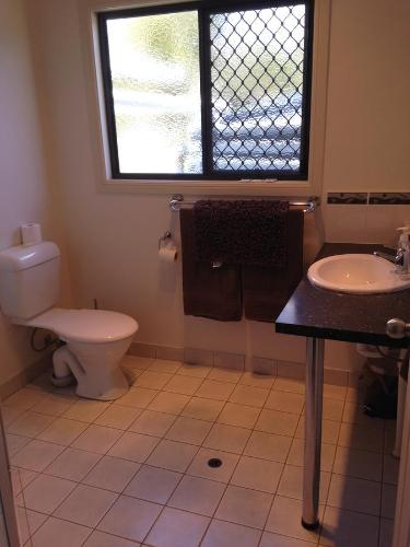 a bathroom with a toilet and a sink and a window at Horsepower Cabins in Warwick