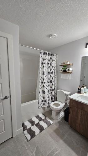a bathroom with a toilet and a shower curtain at Brand New Stylish Heartland Suite! in Regina