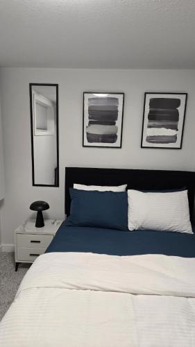 a bedroom with a bed with two pictures on the wall at Brand New Stylish Heartland Suite! in Regina