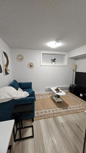 a living room with a blue couch and a table at Brand New Stylish Heartland Suite! in Regina