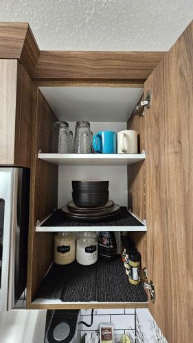 a cupboard with a plate and dishes on it at Brand New Stylish Heartland Suite! in Regina