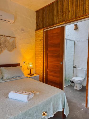a bedroom with a bed and a bathroom with a toilet at Moitas chalés in Amontada