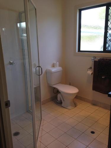 a bathroom with a toilet and a glass shower at Horsepower Cabins in Warwick