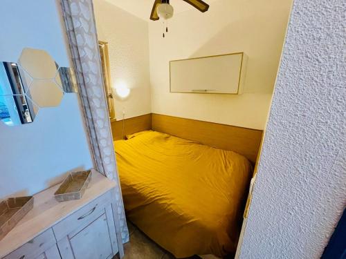 Cette petite chambre comprend un lit jaune et un miroir. dans l'établissement Le Golfe - Ile des Loisirs - Clim - Piscine - Luna Park, au Cap d'Agde