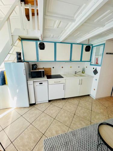 une cuisine avec des armoires blanches et un évier dans l'établissement Le Golfe - Ile des Loisirs - Clim - Piscine - Luna Park, au Cap d'Agde