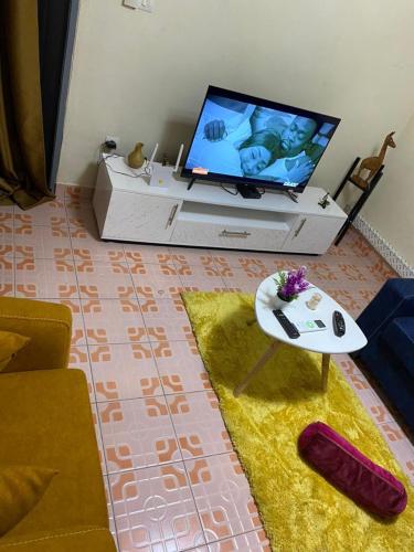 a living room with a tv and a couch and a table at Appartement Performance in Cotonou
