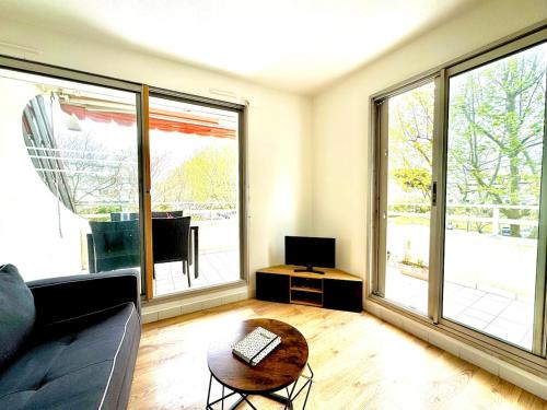 a living room with a couch and large windows at Petite Calédonie-Clim-Proche mer in La Grande-Motte