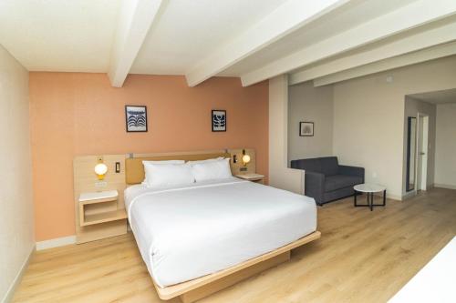 a bedroom with a large white bed and a chair at Ramada by Wyndham Davenport Orlando South in Davenport
